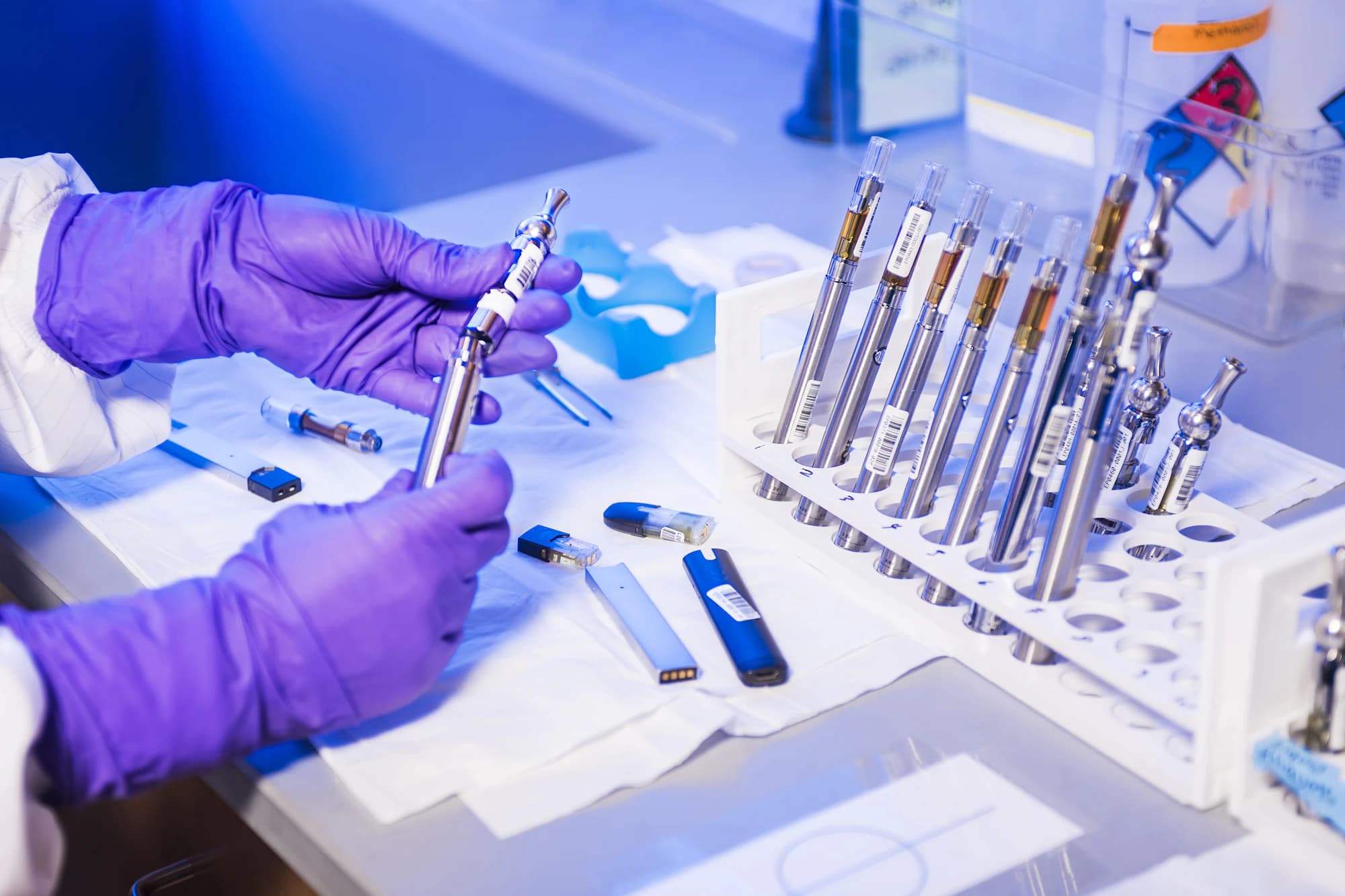 Gloved hands handling steel surgical instruments in racks on a sterile processing bench.