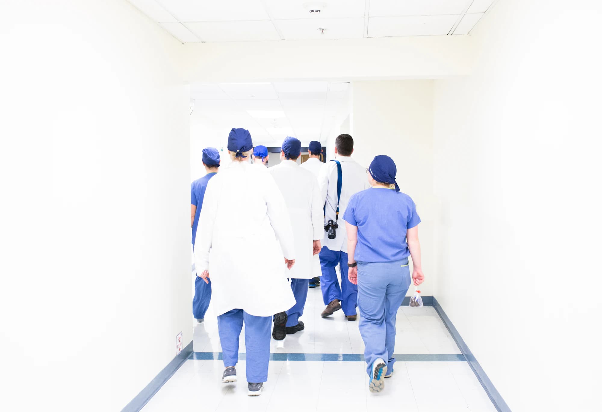 Clinical staff walking away down a bright hospital corridor.