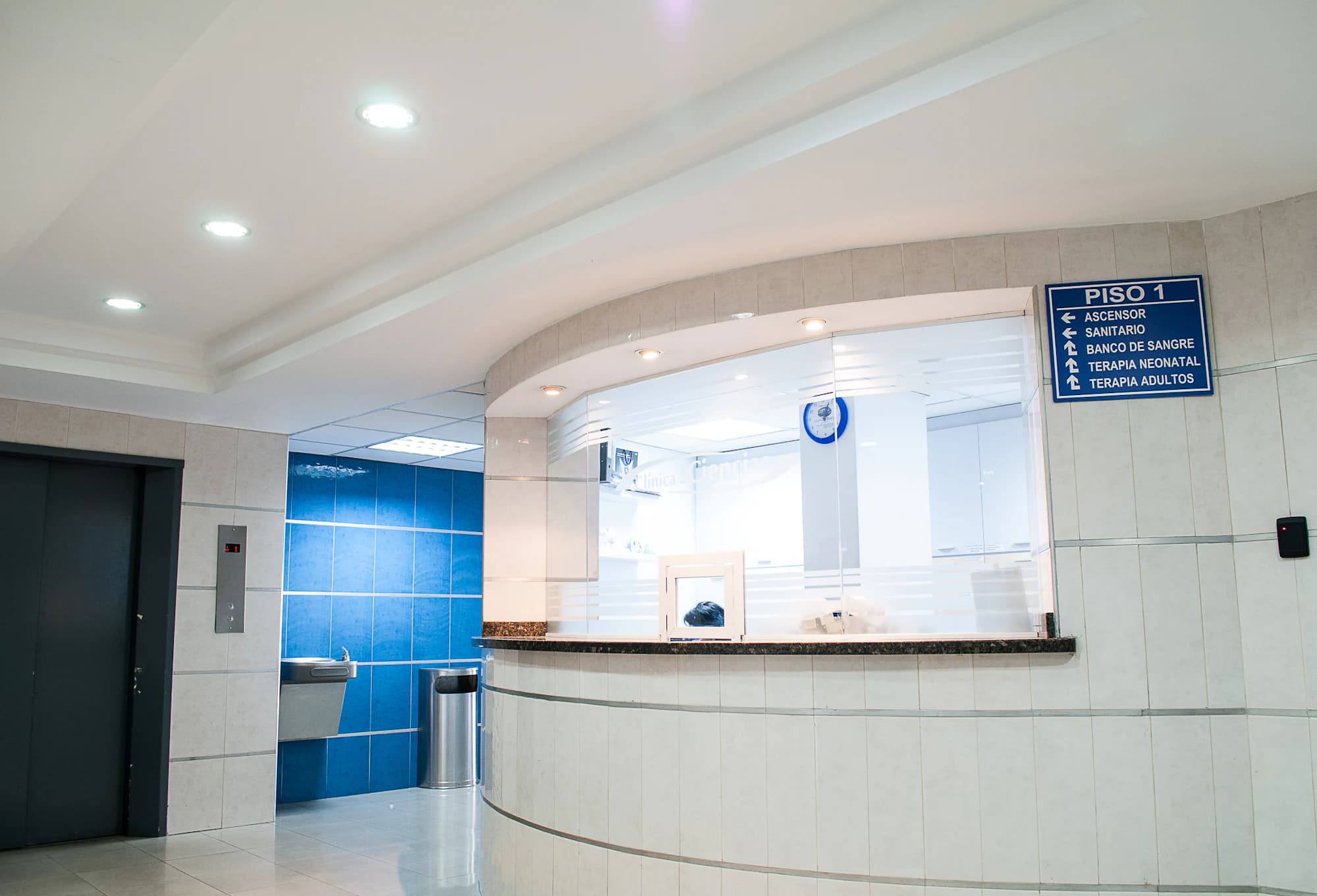 The reception counter of a hospital outpatient department, with the enquiry desk and the signage board behind it.