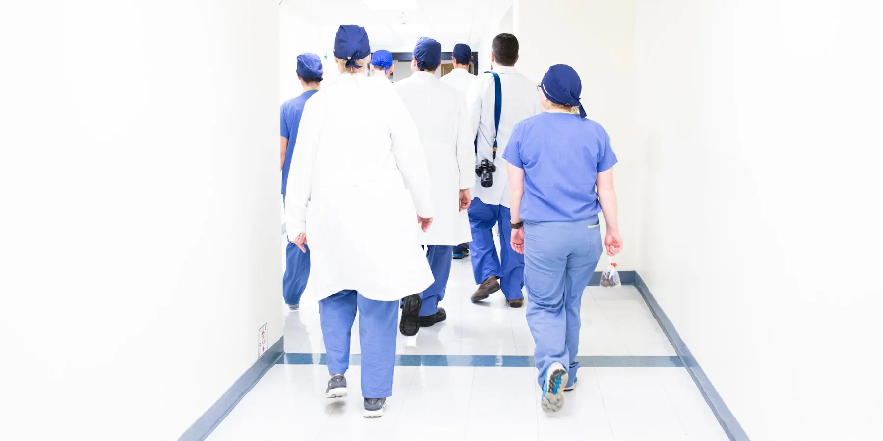 Staff walking a hospital corridor away from the camera.