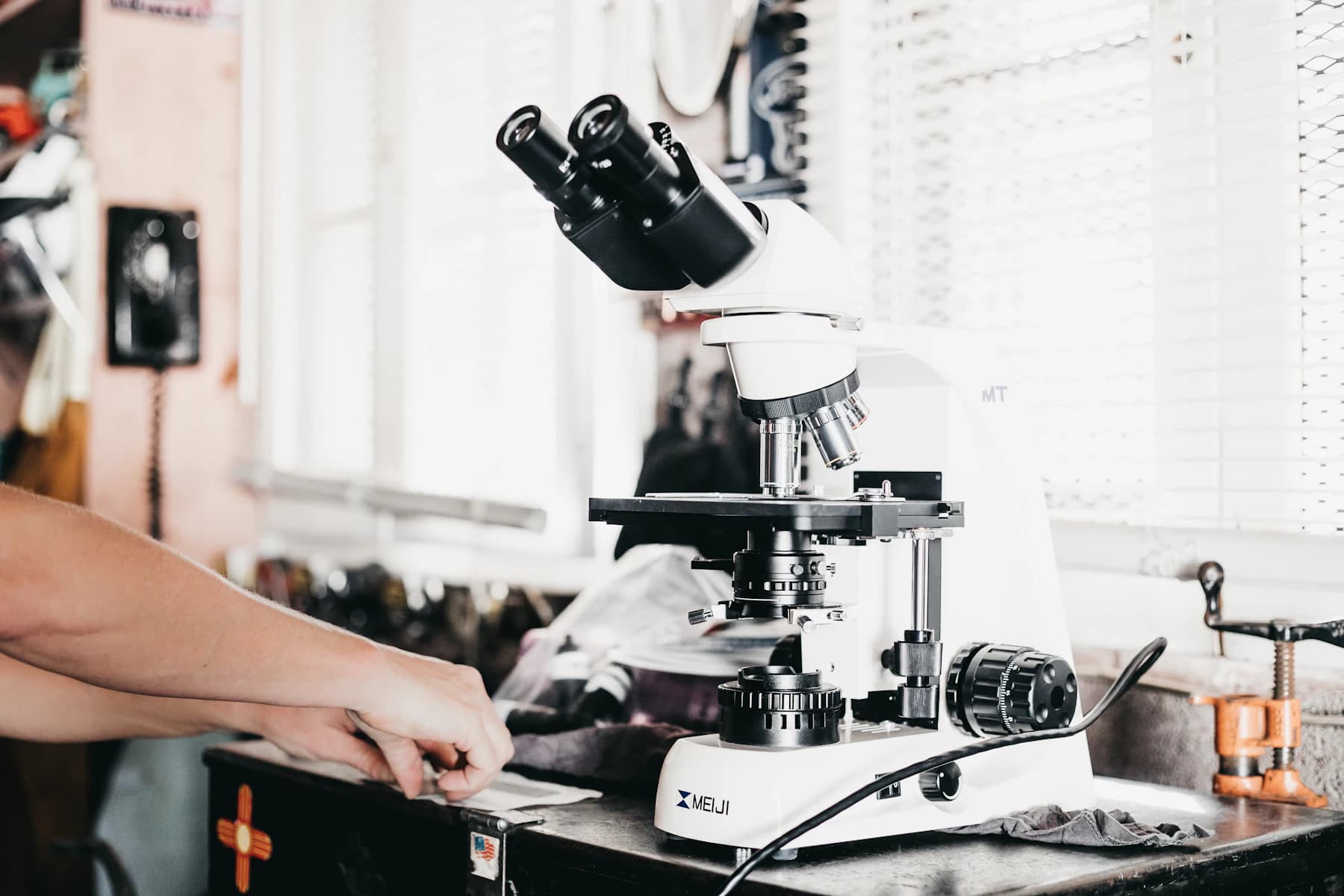 A microscope on a laboratory bench beside a set of prepared slides.