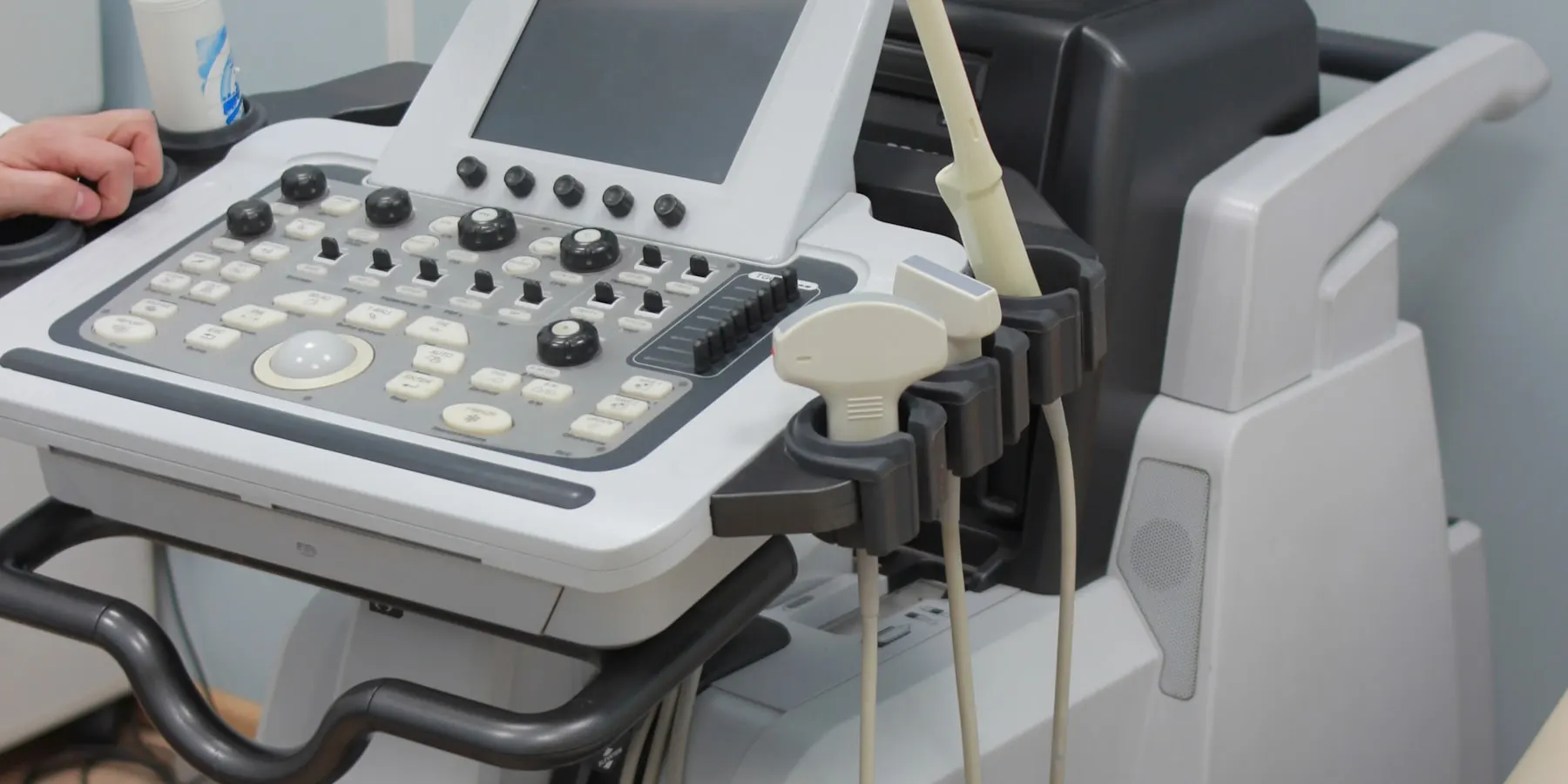 An ultrasound console and its probe in an examination room.