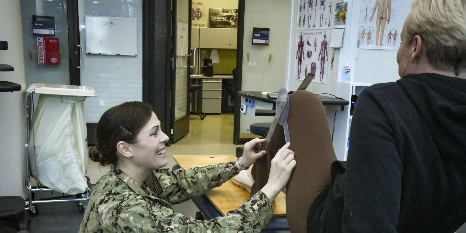 A therapist assessing a patient limb in a clinic room.