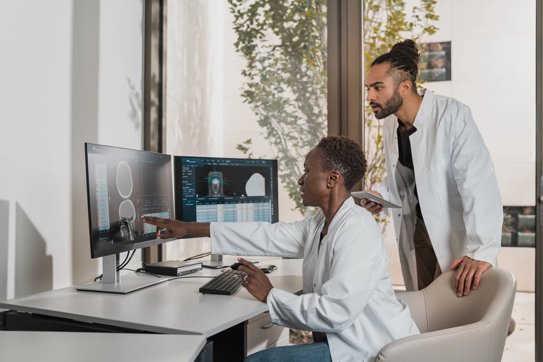 Two clinicians at an imaging workstation reviewing a reconstructed study.