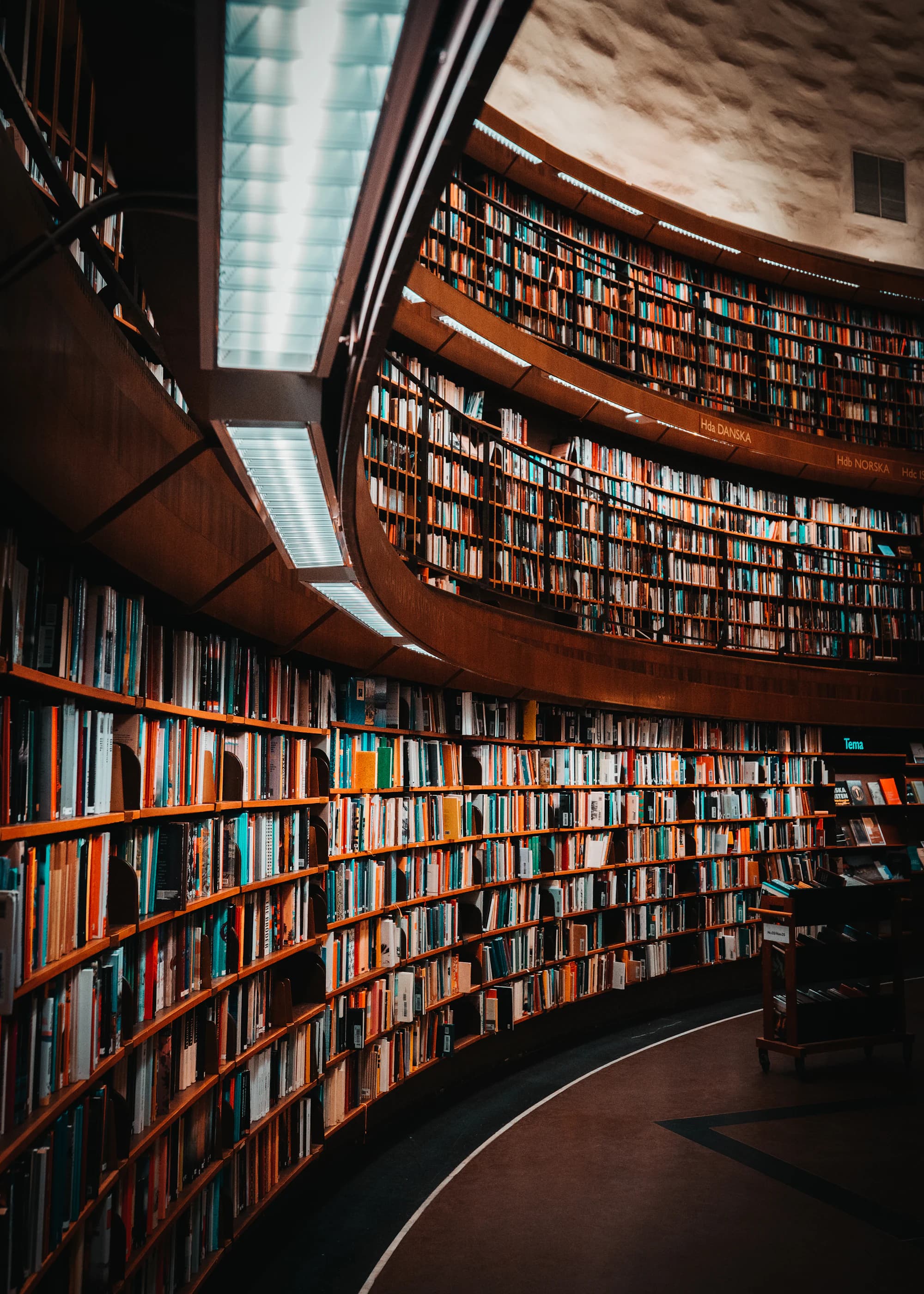 The curved shelves of a large archive reading room, filled with bound volumes from floor to ceiling.