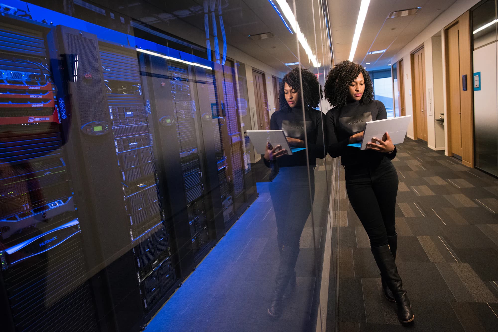 Two people walking a data centre aisle with laptops open.