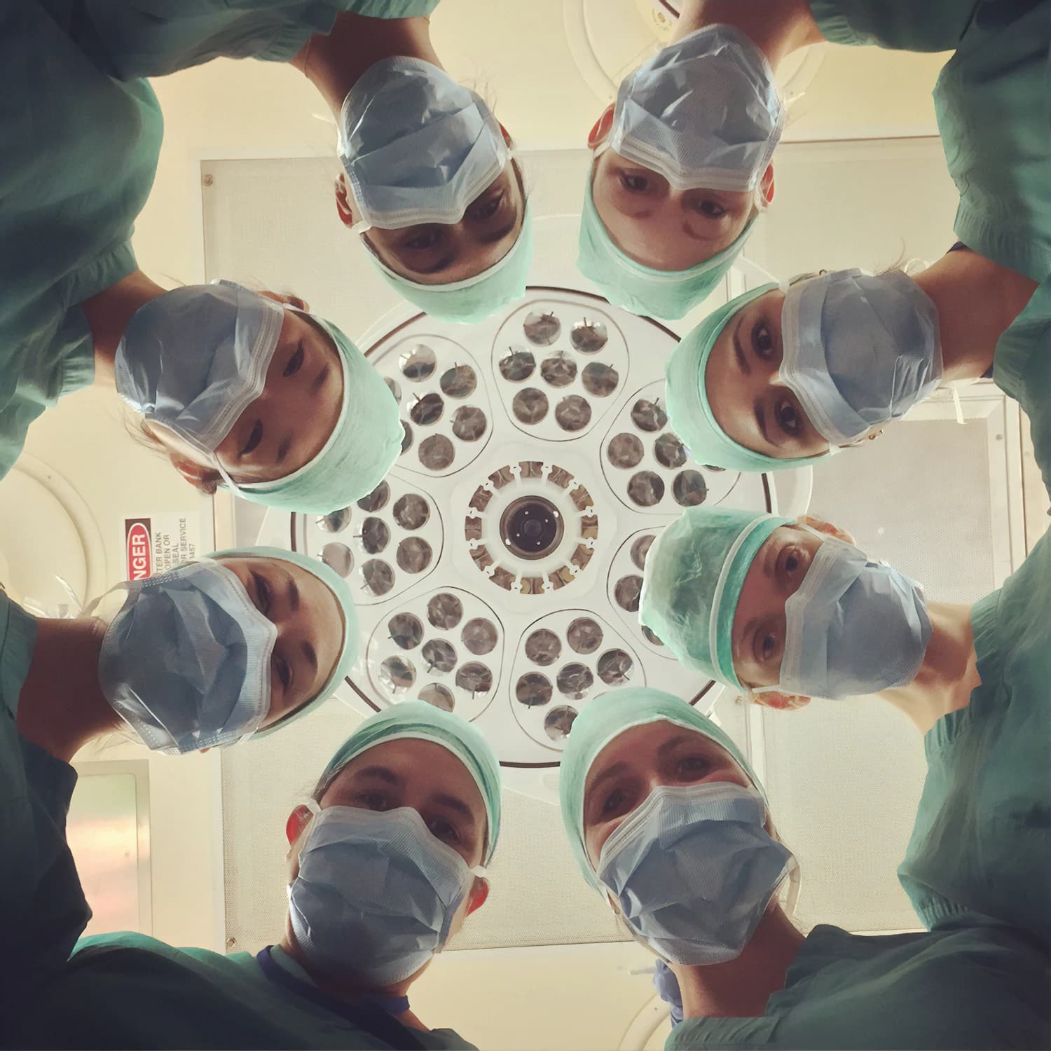 A surgical team seen from the operating table, gathered under the theatre lights.