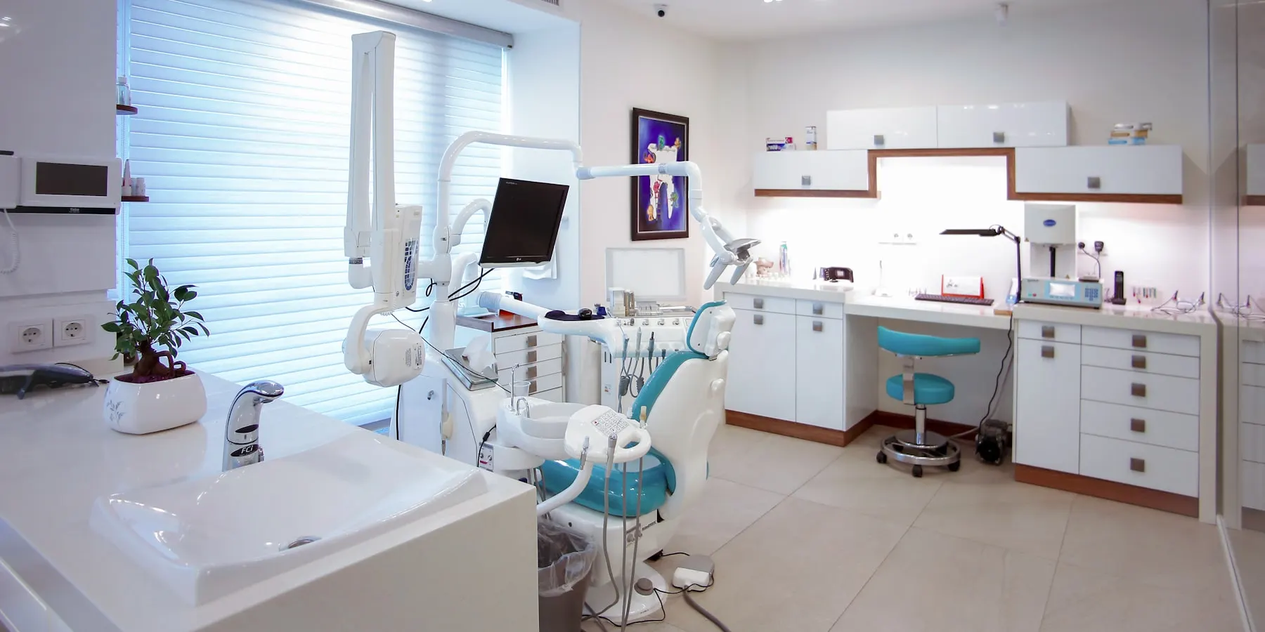 A dental surgery with the chair, the light and the cabinetry.