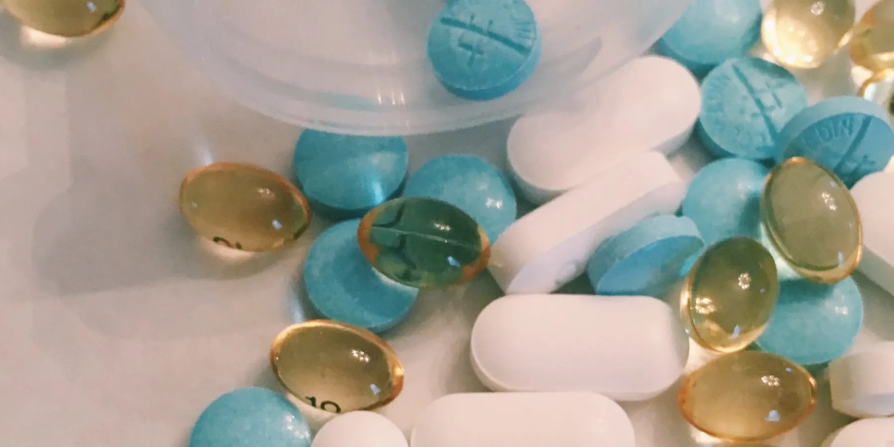 Tablets and capsules spilling from an opened bottle.
