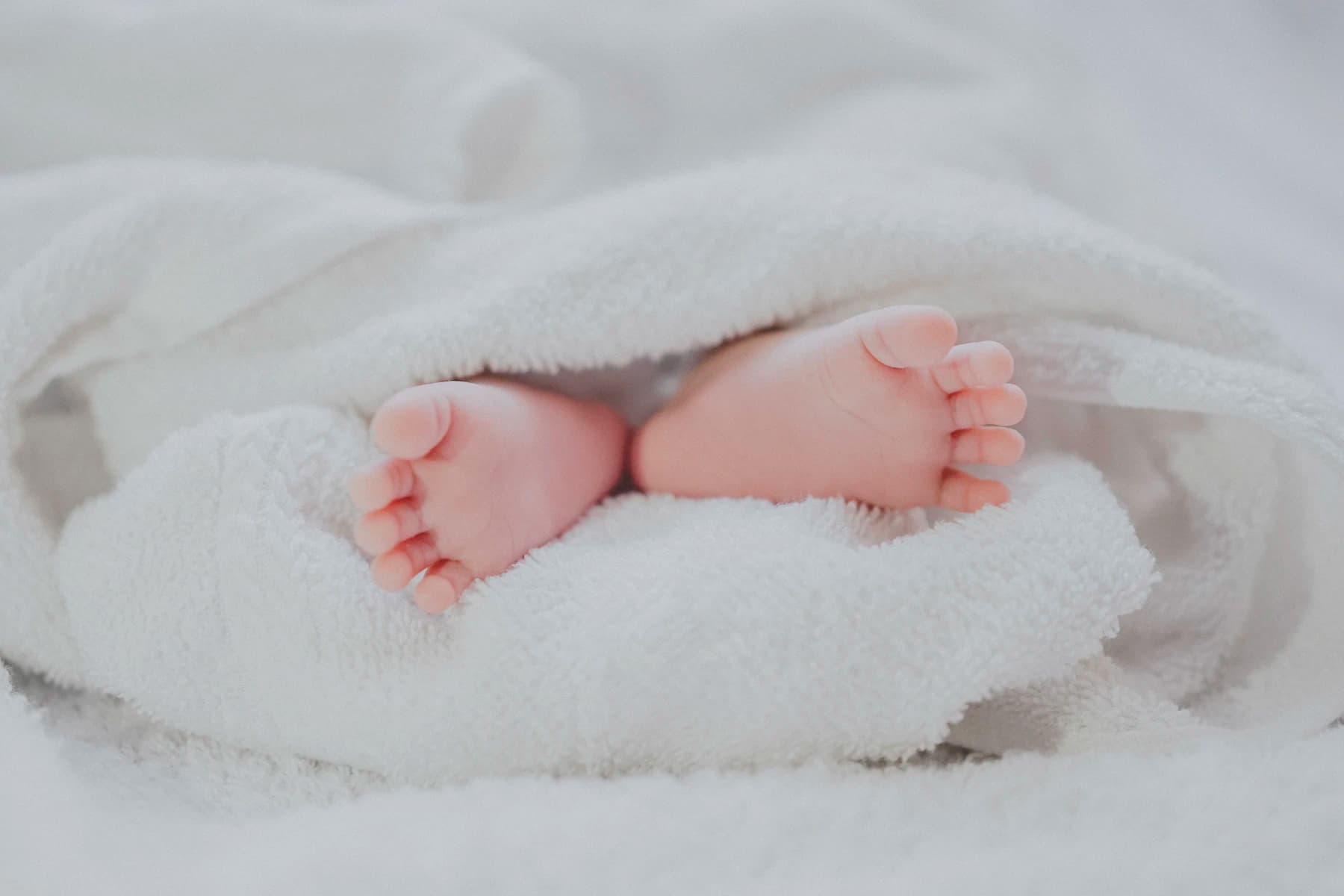 A newborn wrapped in a white hospital towel shortly after delivery.