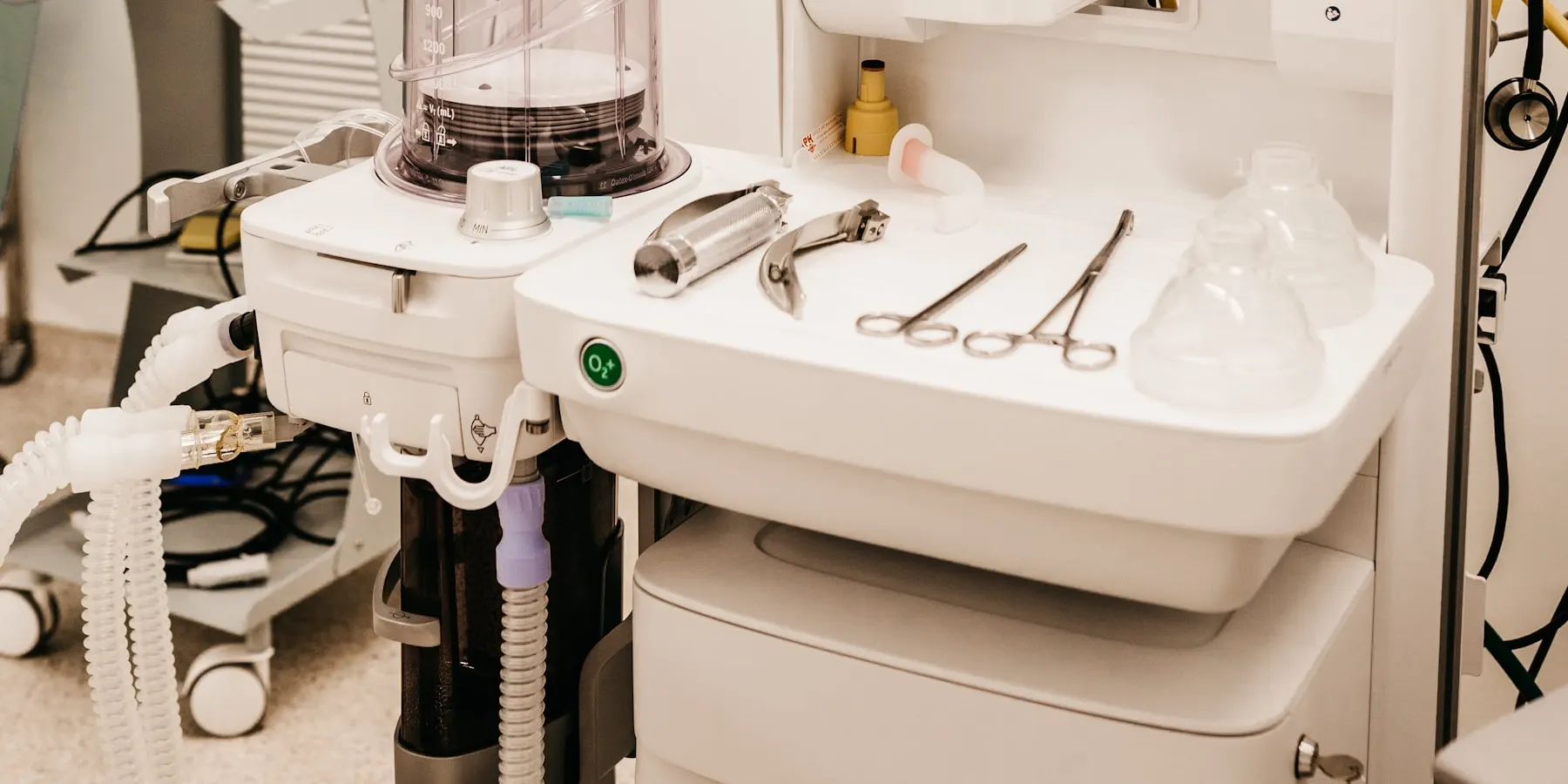 An anaesthetic machine and a laid instrument tray in a theatre.